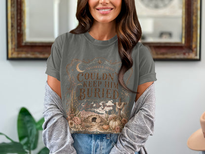 T-shirt with text "Couldn't Keep Him Buried" and Halloween Jesus graphics.