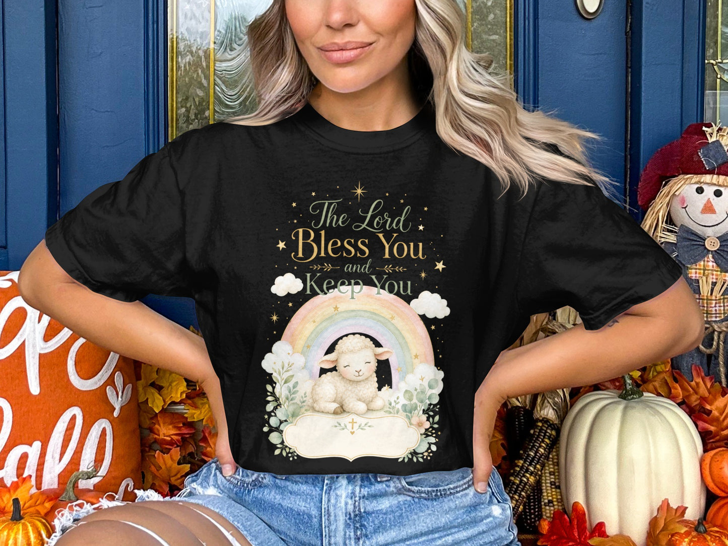 Black t-shirt with a lamb, rainbow, text, and clouds graphic.