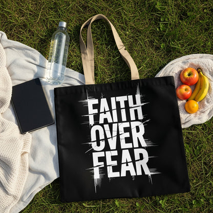 Black tote bag with "FAITH OVER FEAR" text, fruits, and water bottle on grass.