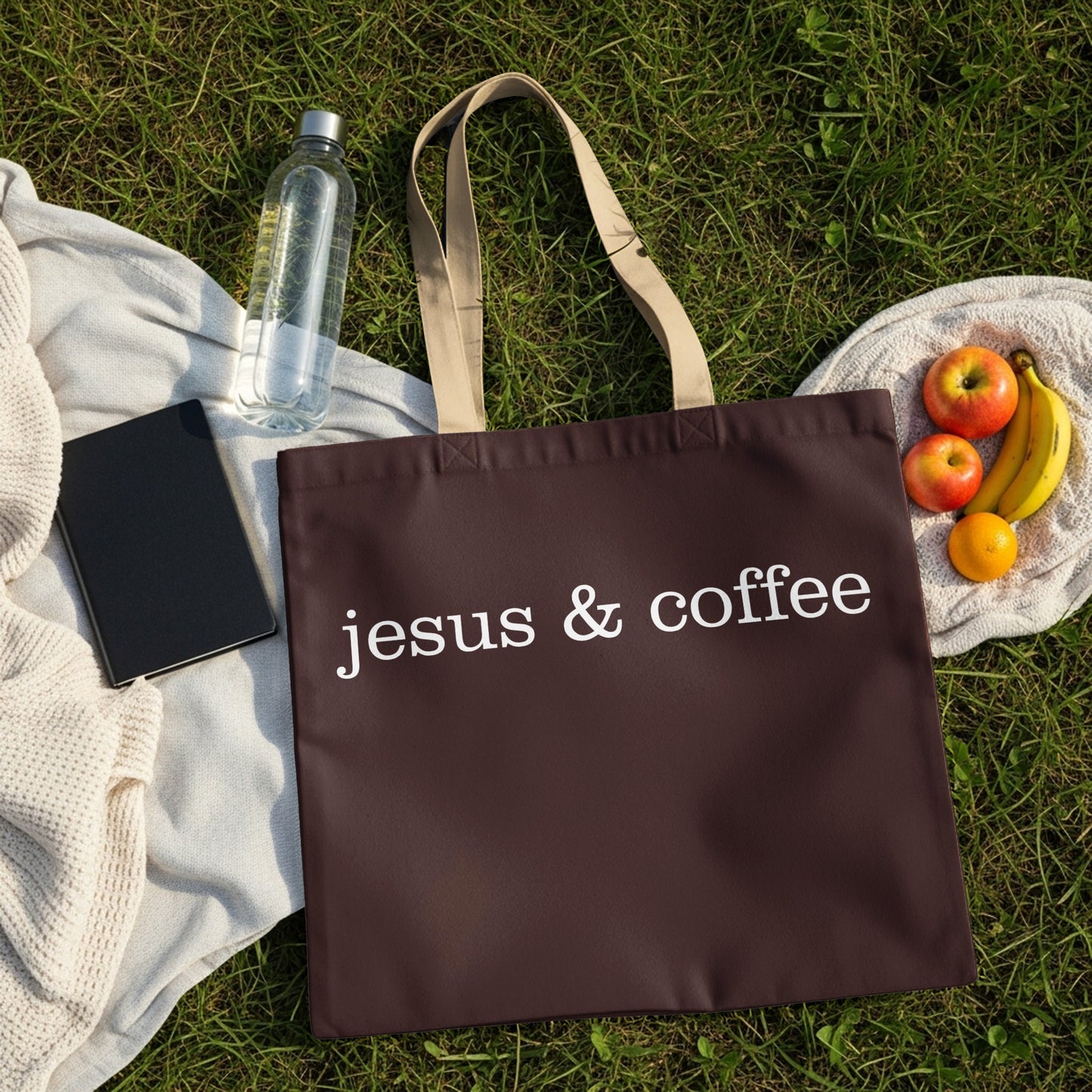 Brown tote bag with white text "jesus & coffee" on grass