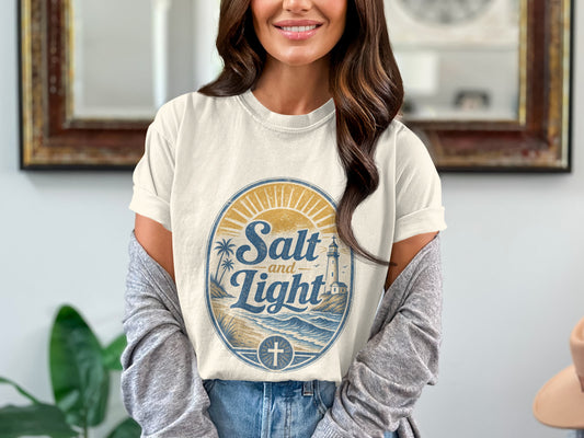 Cream t-shirt with "Salt and Light" oval graphic featuring a lighthouse and cross emblem.
