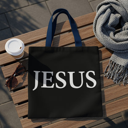 Black tote bag with "JESUS" in white lettering, blue straps.