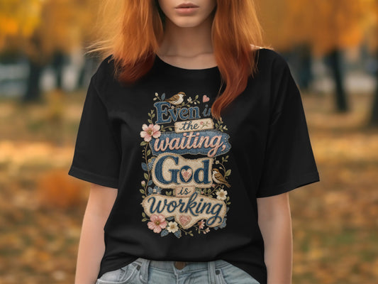 Black t-shirt with "Even in the waiting, God is working" text and floral embellishments.