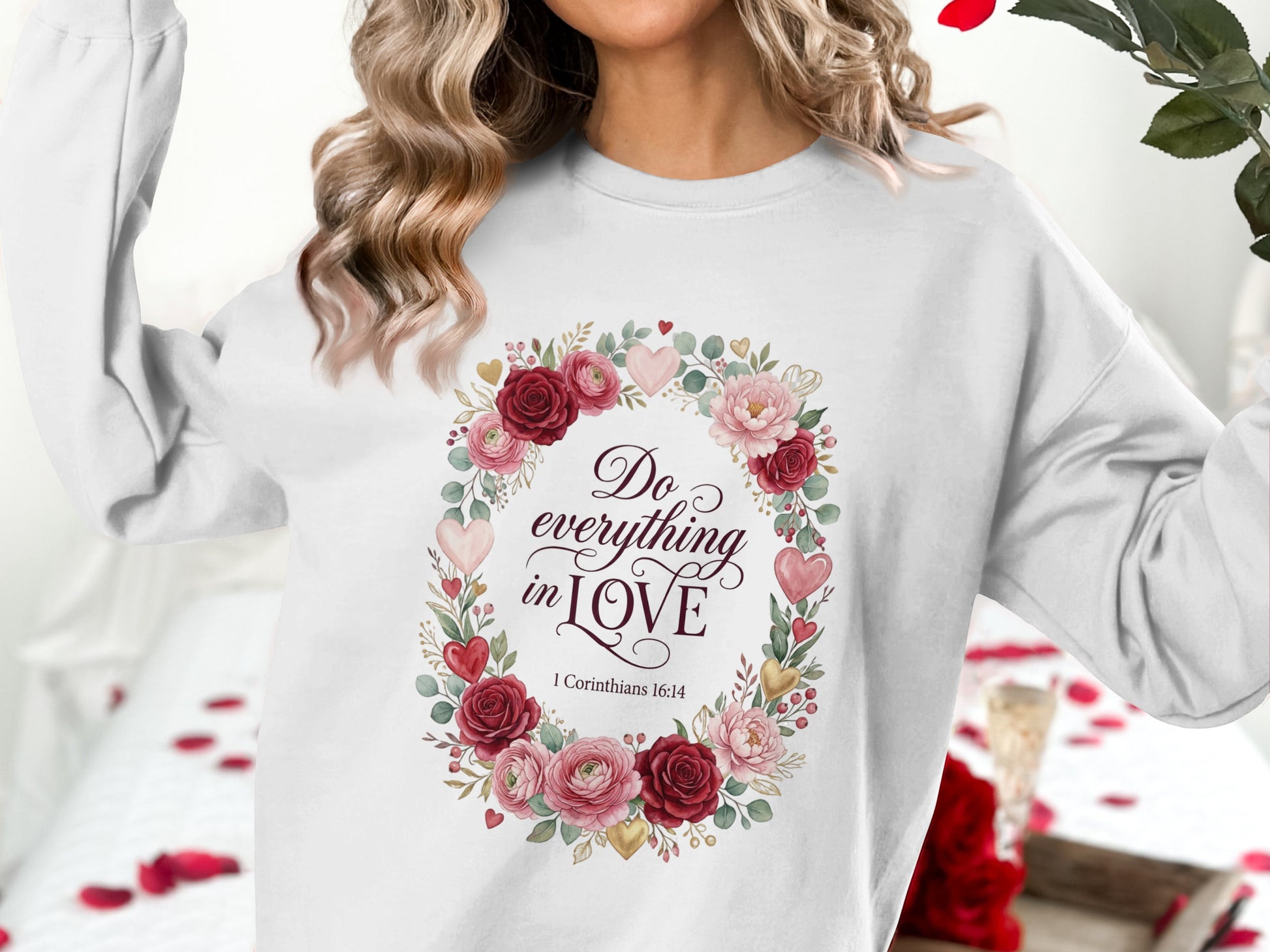 White sweatshirt with floral wreath saying "Do everything in love 1 Corinthians 6:14".