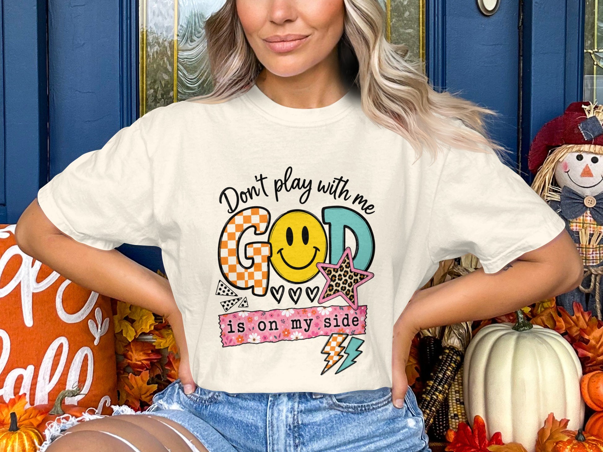 Cream t-shirt with "God is on my side" graphic and smiley face.