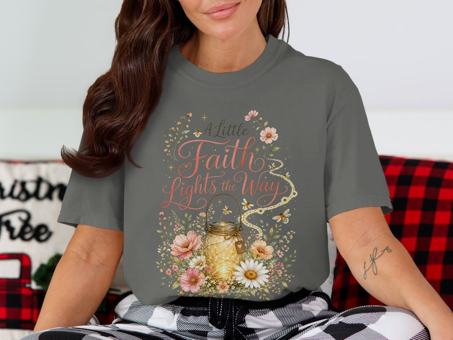 T-shirt graphic: A lit jar surrounded by flowers, with text "A Little Faith Lights the Way".