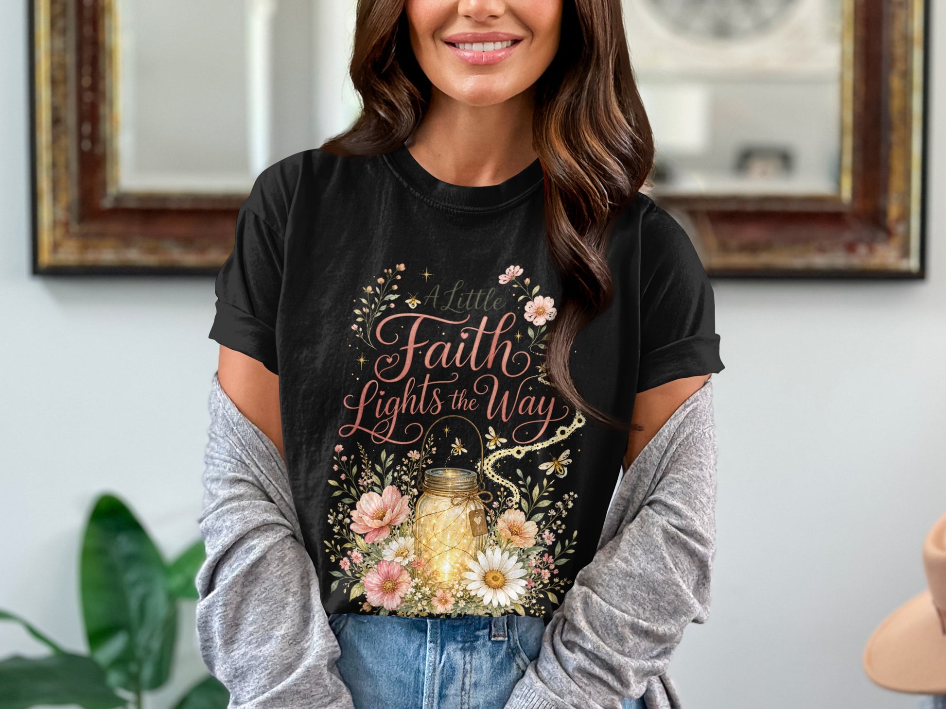 Black t-shirt featuring a mason jar with lights, flowers, and text "A Little Faith Lights the Way."