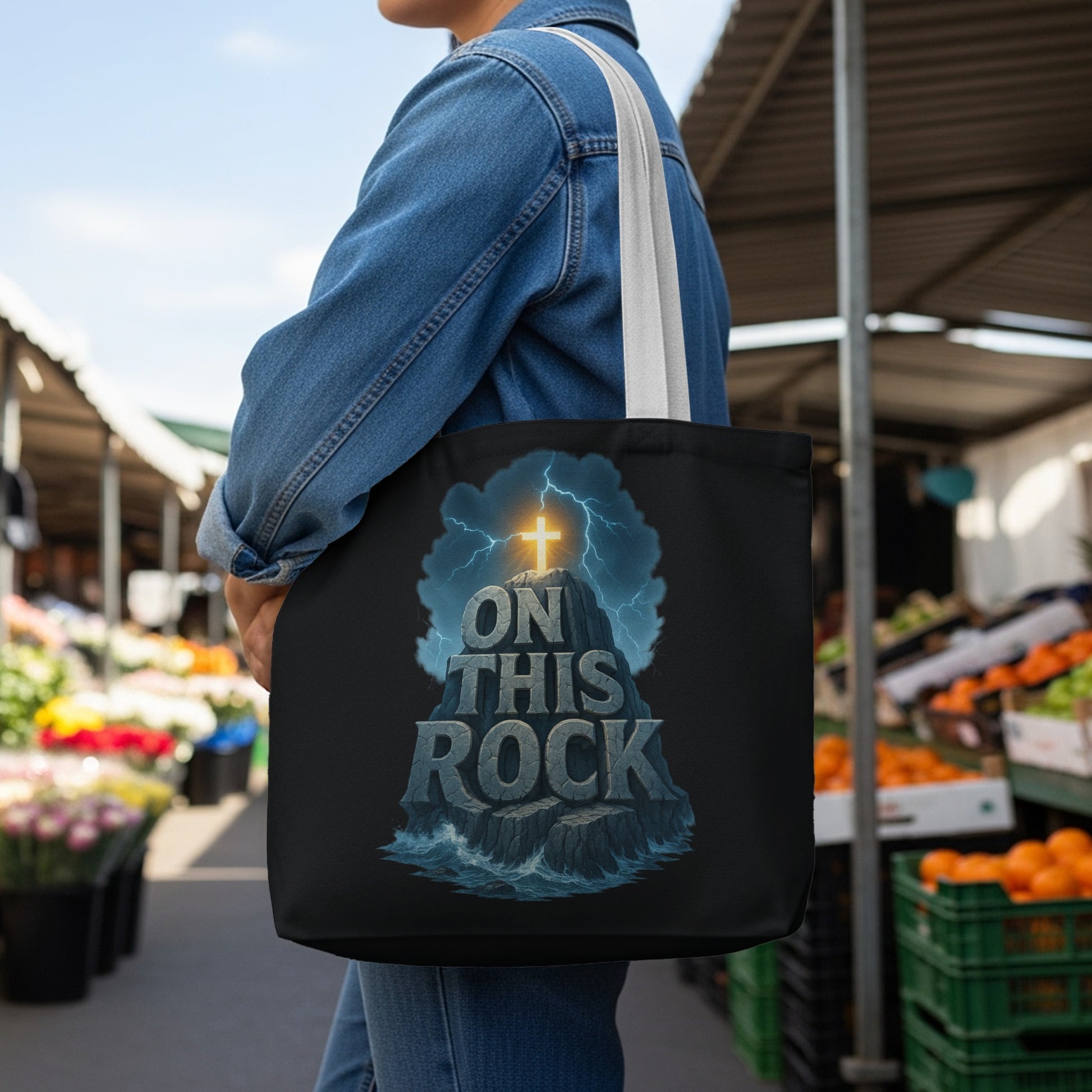Black tote bag with "ON THIS ROCK" text and a cross on a stormy mountain.