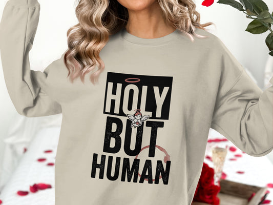 Cream sweatshirt with "Holy But Human" text and angel graphic.