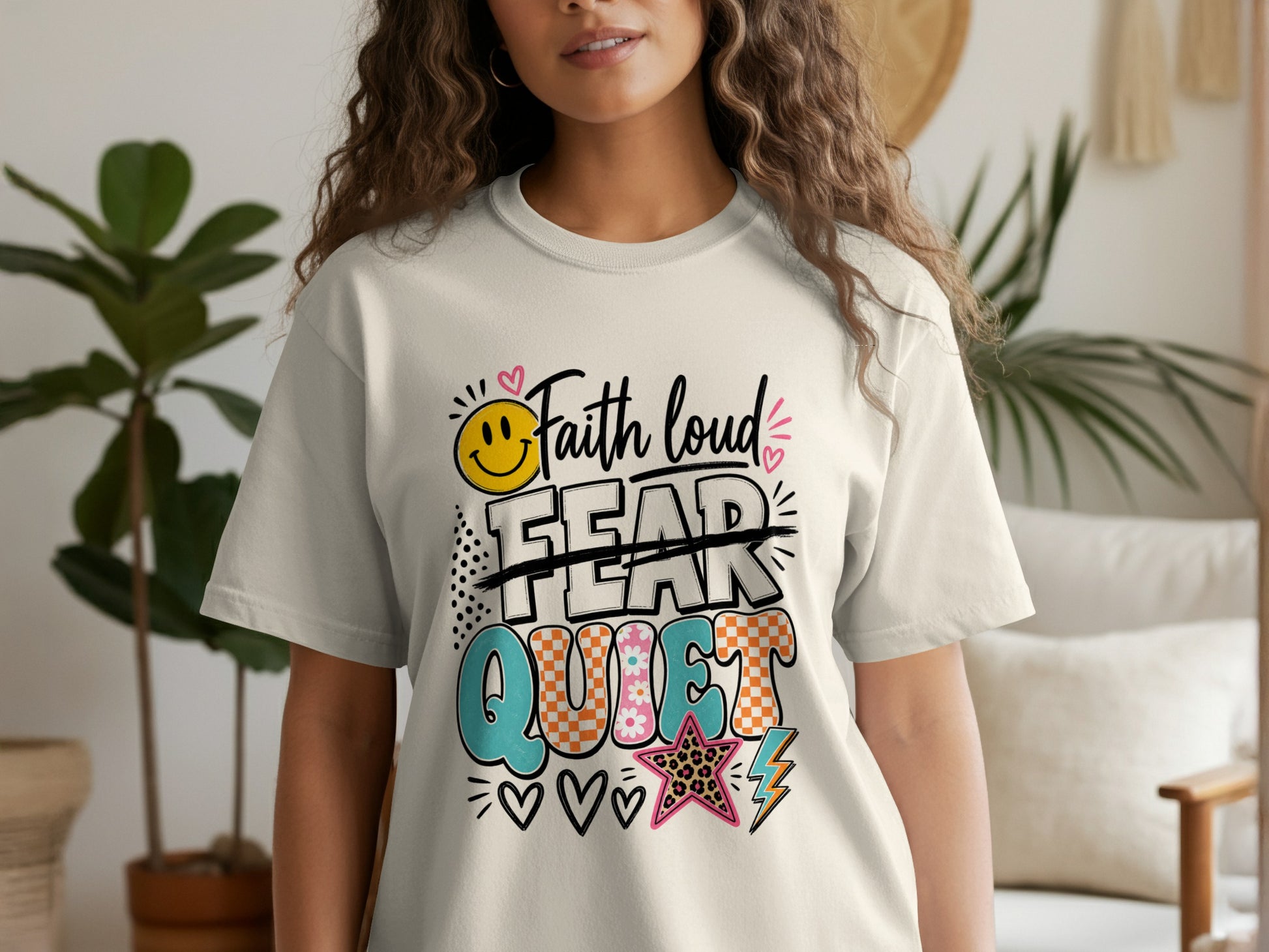 Faith loud, crossed-out fear, and the word quiet on a cream t-shirt.