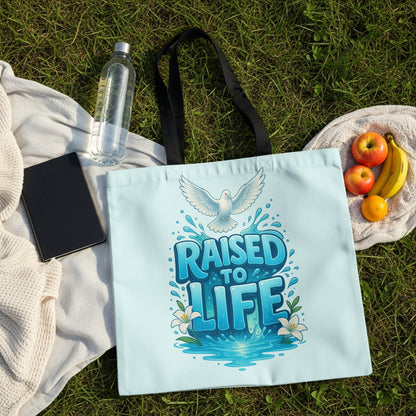 Light blue tote bag with "RAISED TO LIFE" text, dove, and lilies.
