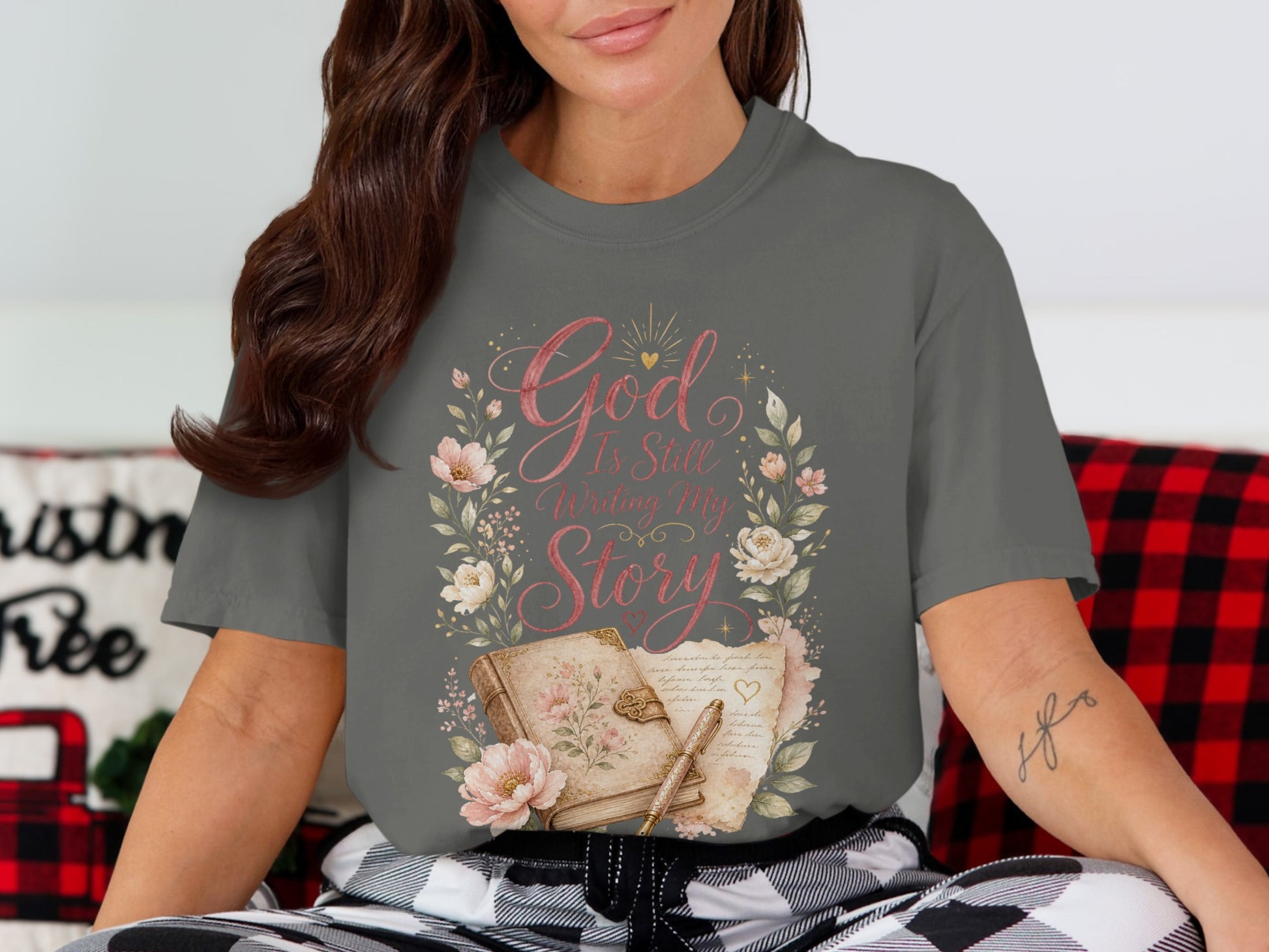 Gray t-shirt with floral wreath, book, pen, and text "God Is Still Writing My Story".