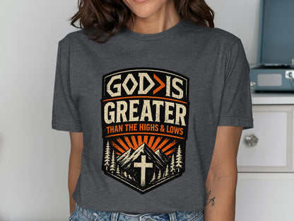Dark gray t-shirt with "GOD IS GREATER THAN THE HIGHS & LOWS" text and mountain graphic.