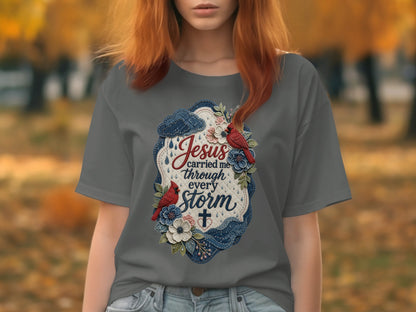 Gray t-shirt with oval design featuring birds, flowers, and text "Jesus carried me through every storm".