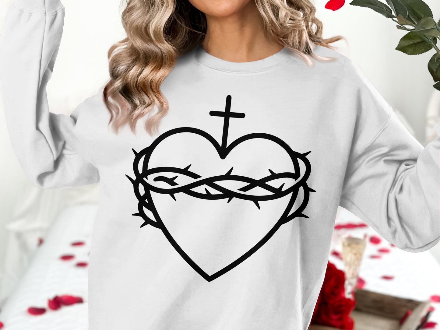 Black line art of a heart with a crown of thorns and a cross.