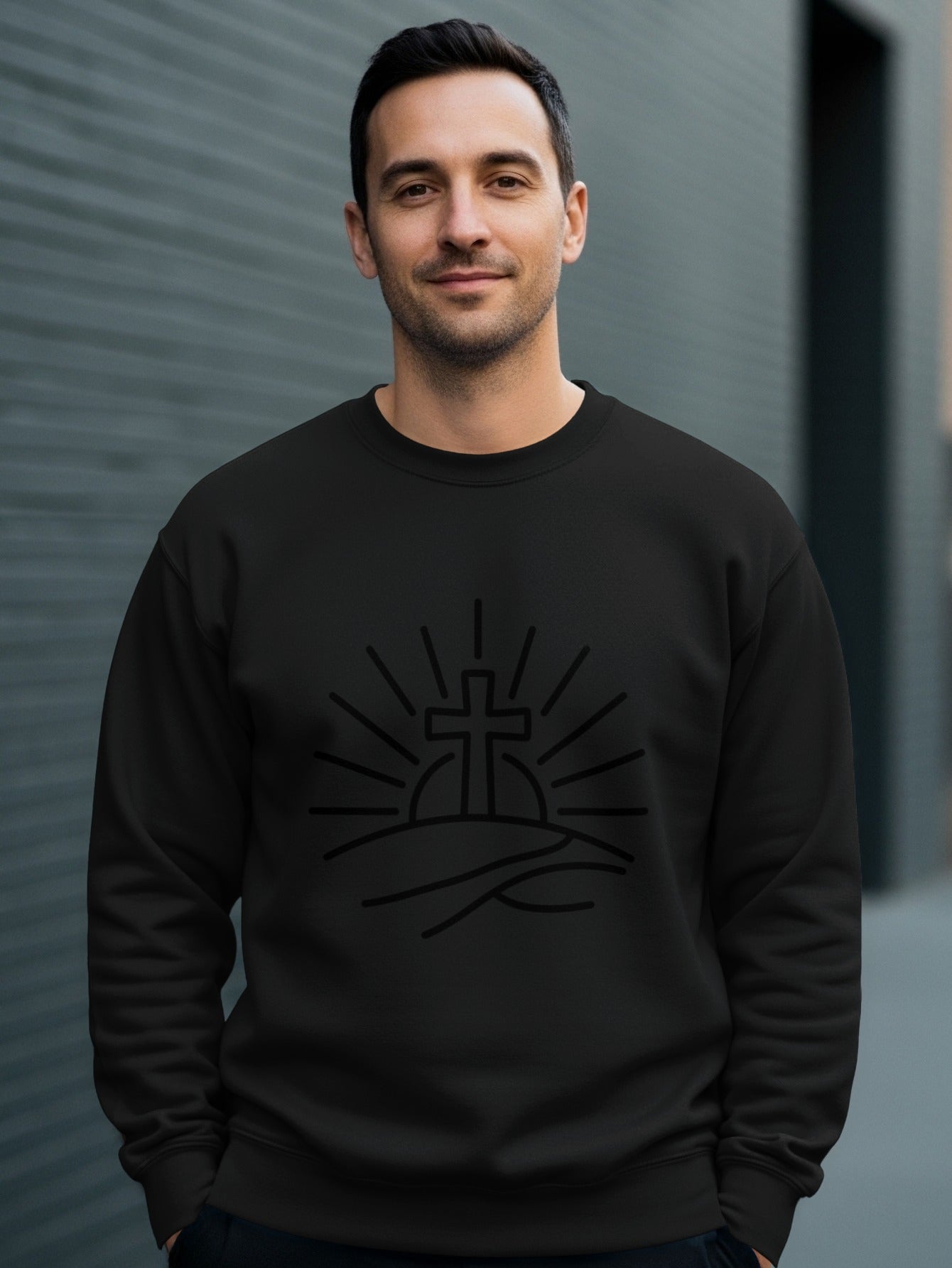Man wearing black crewneck sweatshirt with sun and cross graphic.