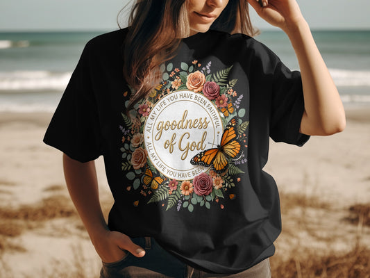 Black t-shirt with floral wreath, butterfly, and "Goodness of God" text.