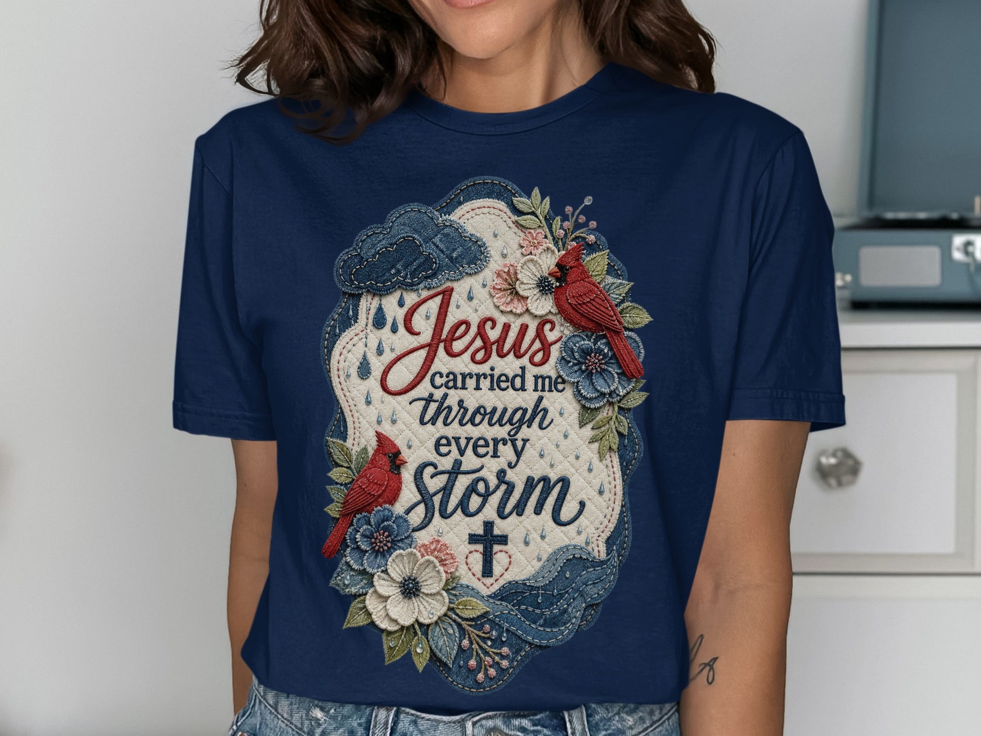 Navy t-shirt with "Jesus carried me through every storm" text and floral and bird design.