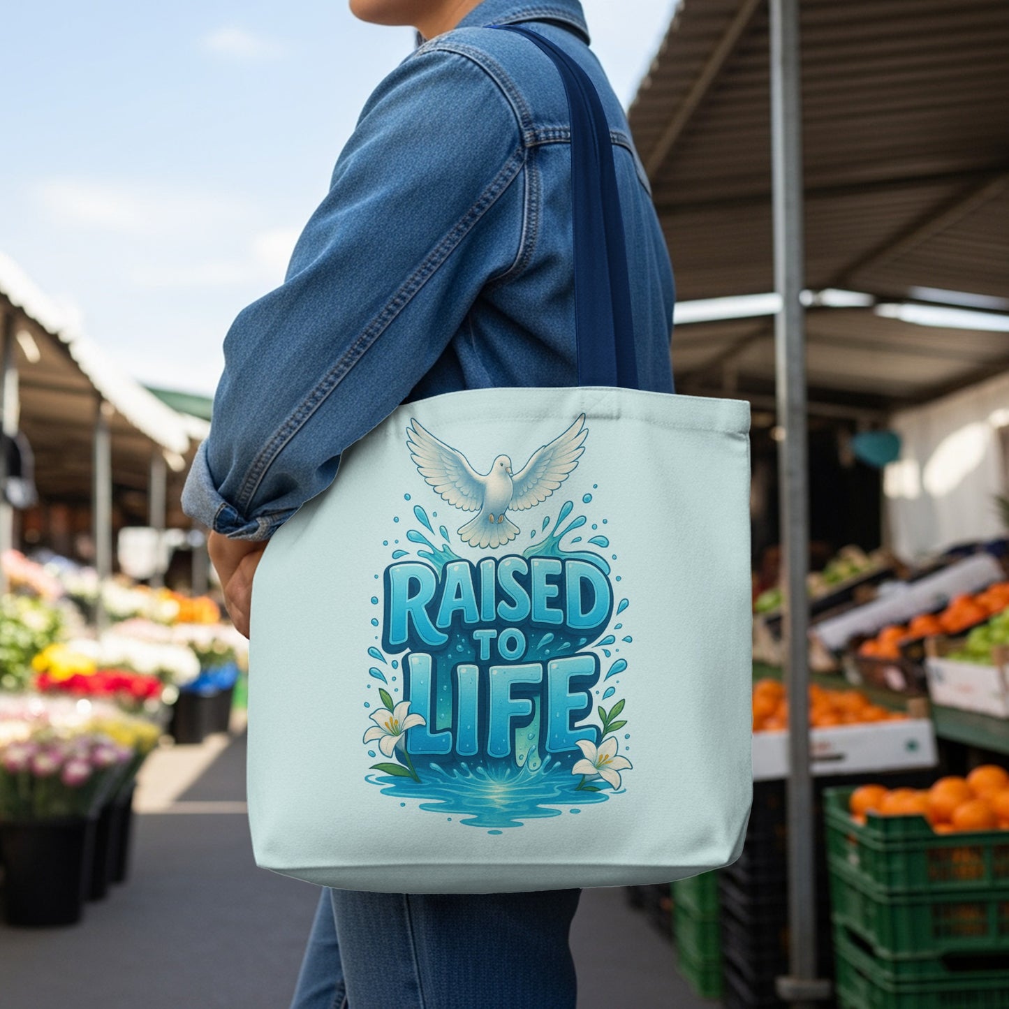 Tote bag with white dove and "Raised to Life" text on a light blue background.
