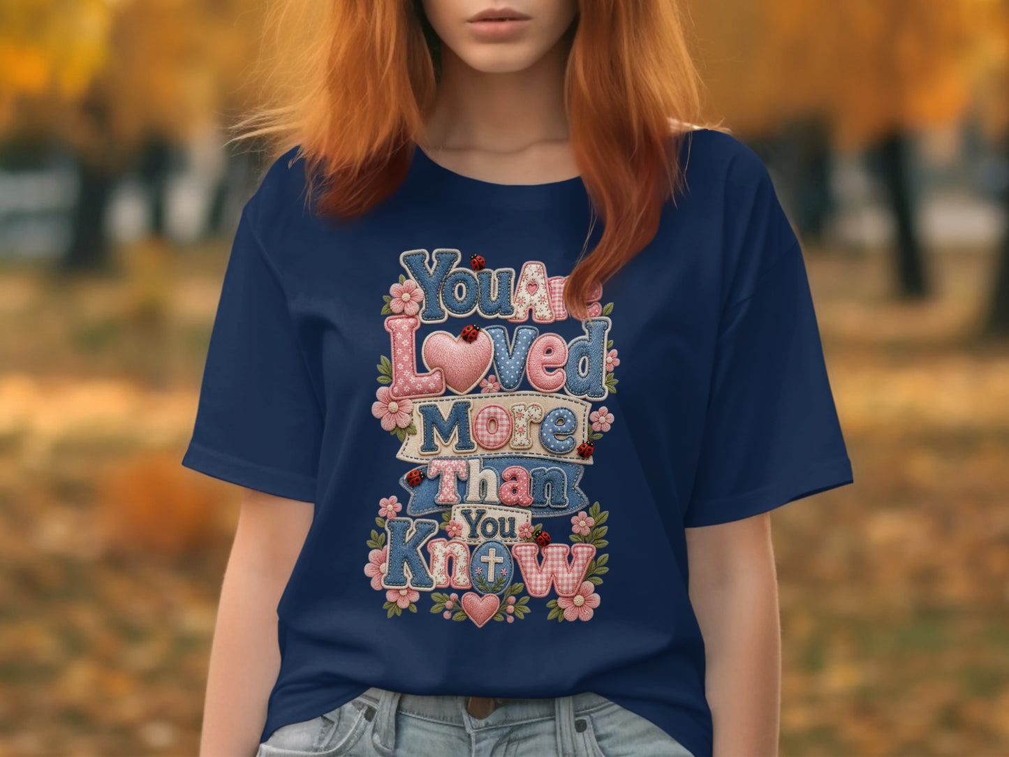 Navy t-shirt with "You Are Loved More Than You Know" text and floral accents.
