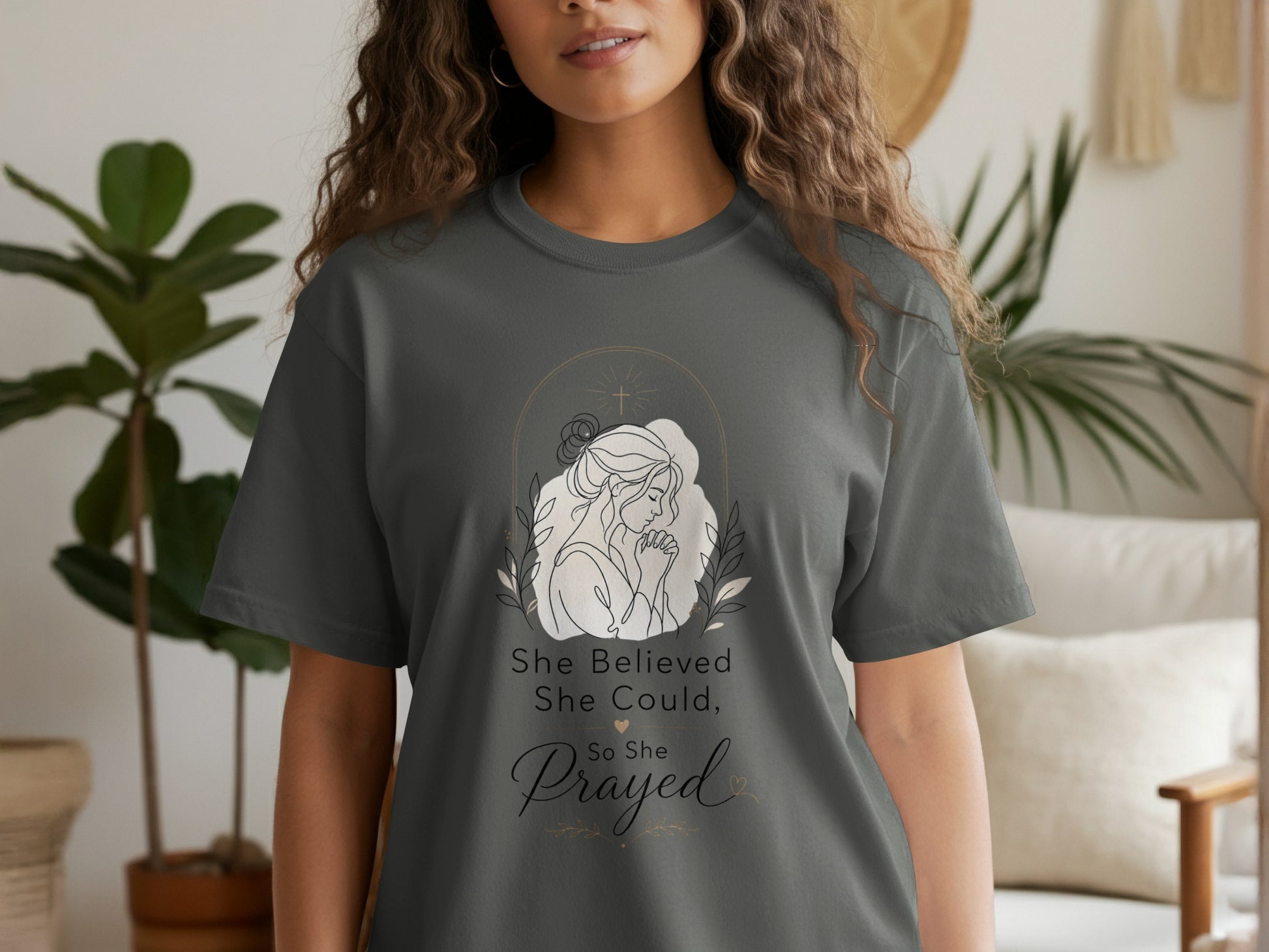 Dark gray t-shirt with line art of a woman praying, cross, and text "She Believed She Could, So She Prayed."