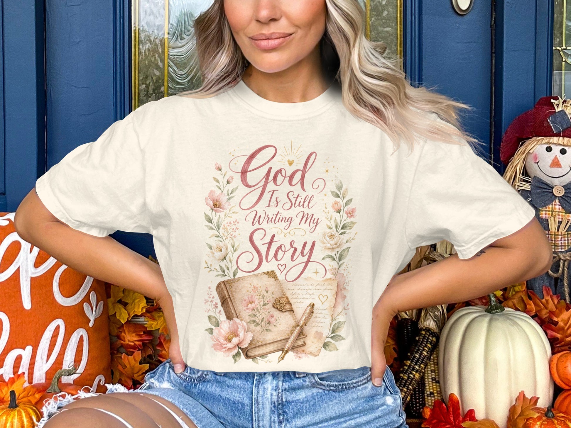 Cream t-shirt with floral wreath graphic and text "God Is Still Writing My Story".