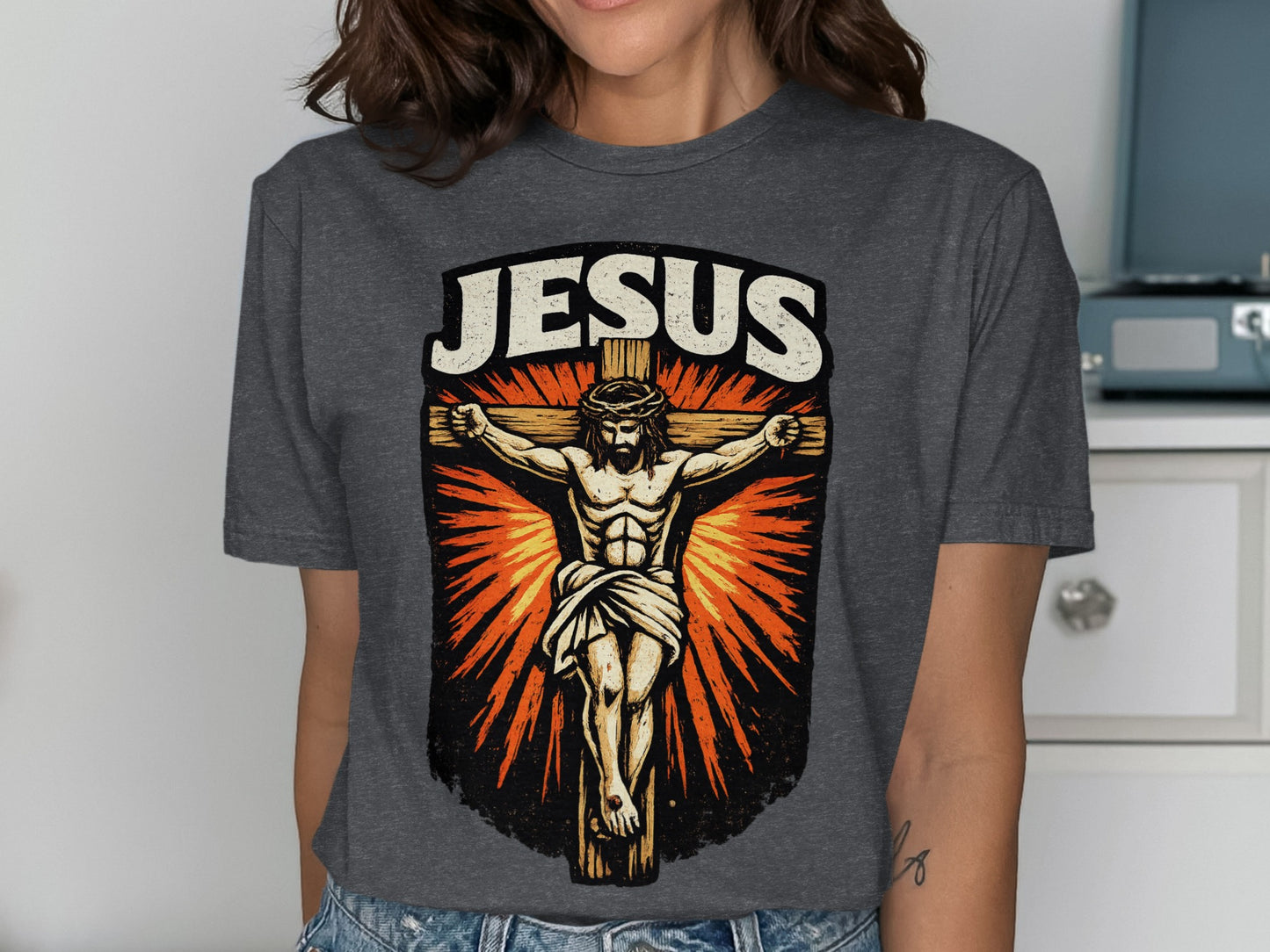 Crucifixion of Jesus Christ with "JESUS" text above, on a dark grey t-shirt.