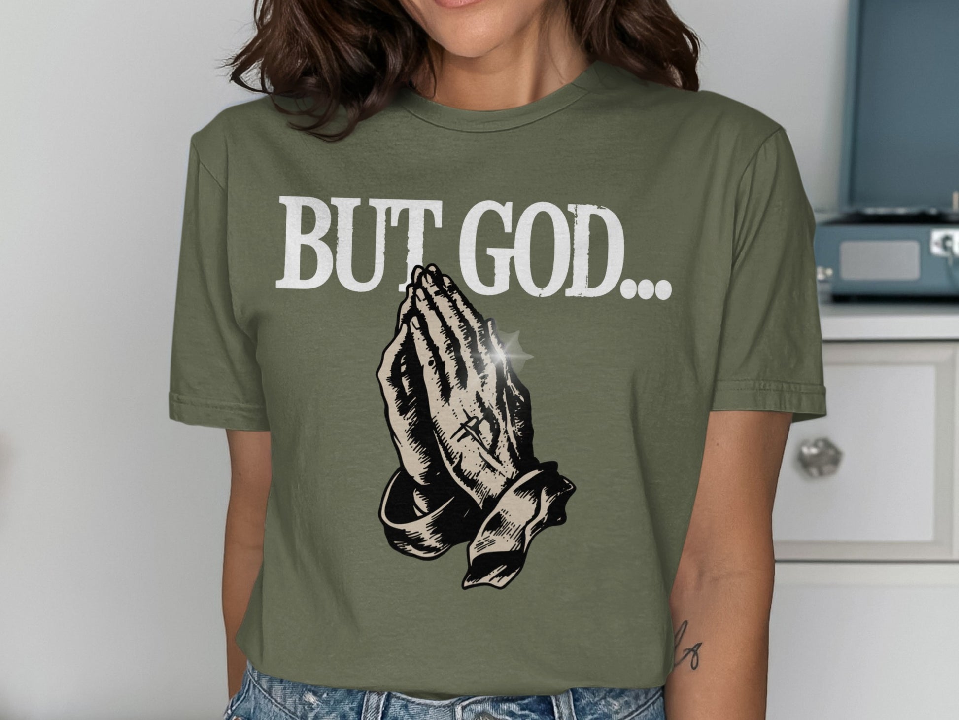 Olive green t-shirt with "BUT GOD..." and praying hands graphic.