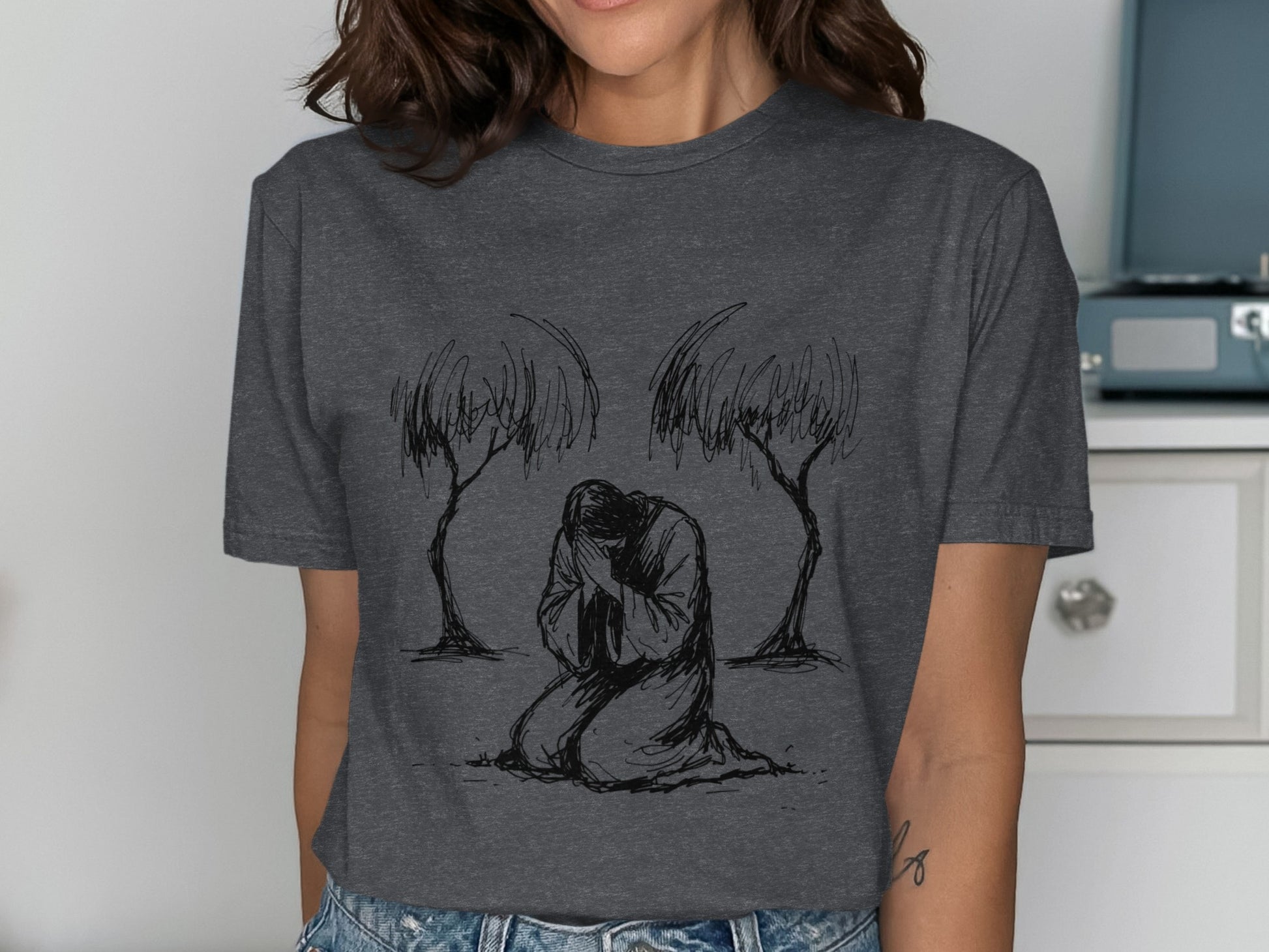Dark grey t-shirt featuring a line drawing of a person kneeling between two trees.