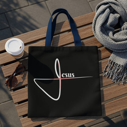 Black tote bag with white and red "Jesus" graphic and blue handles.