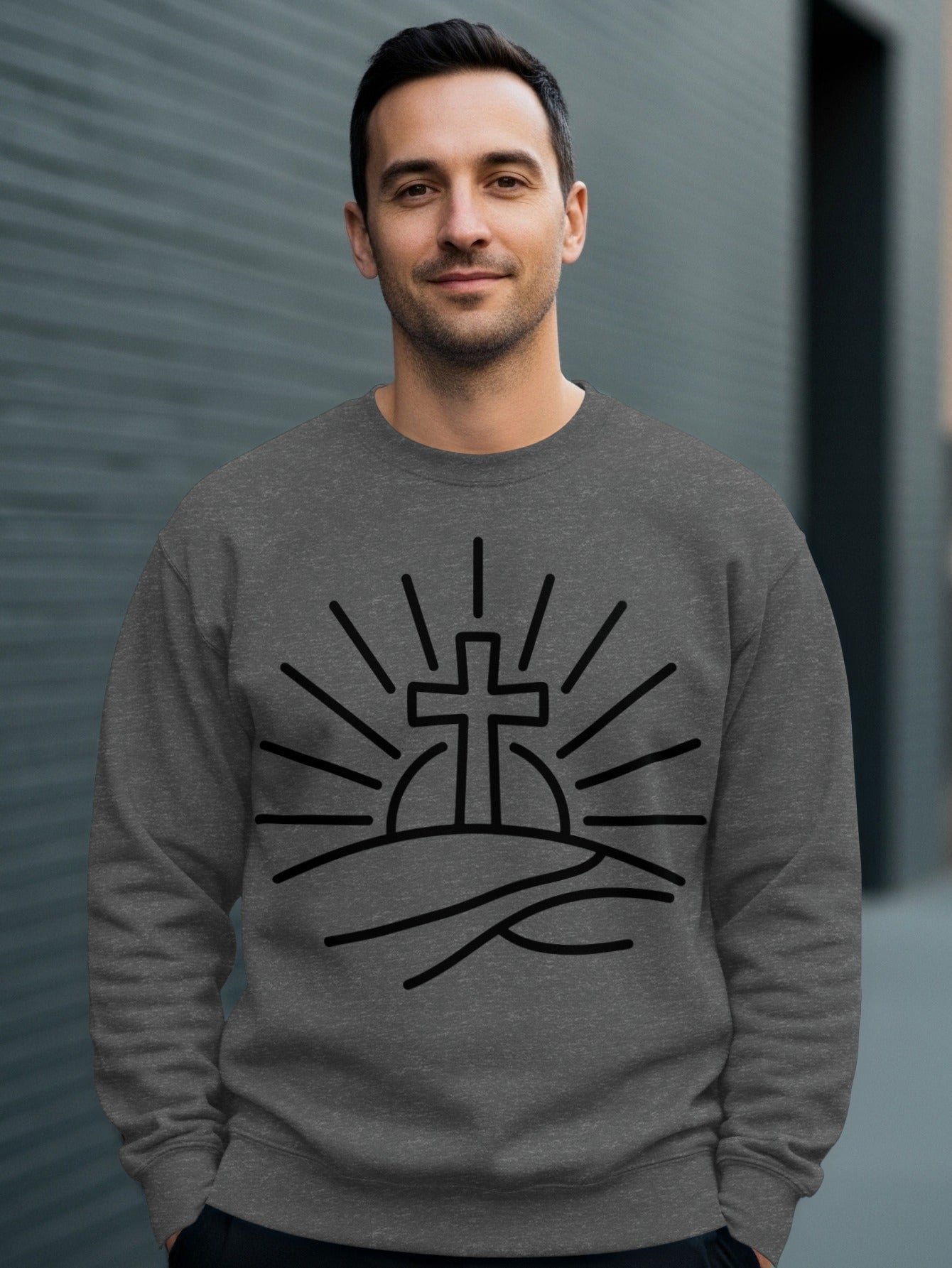 Man wearing a dark gray sweatshirt with a black sunrise and cross graphic.