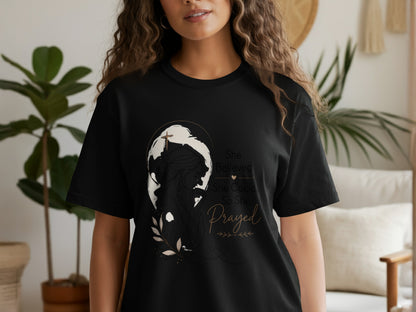 Black t-shirt with graphic: woman praying, cross, globe, and text "She Believed She Could, So She Prayed".