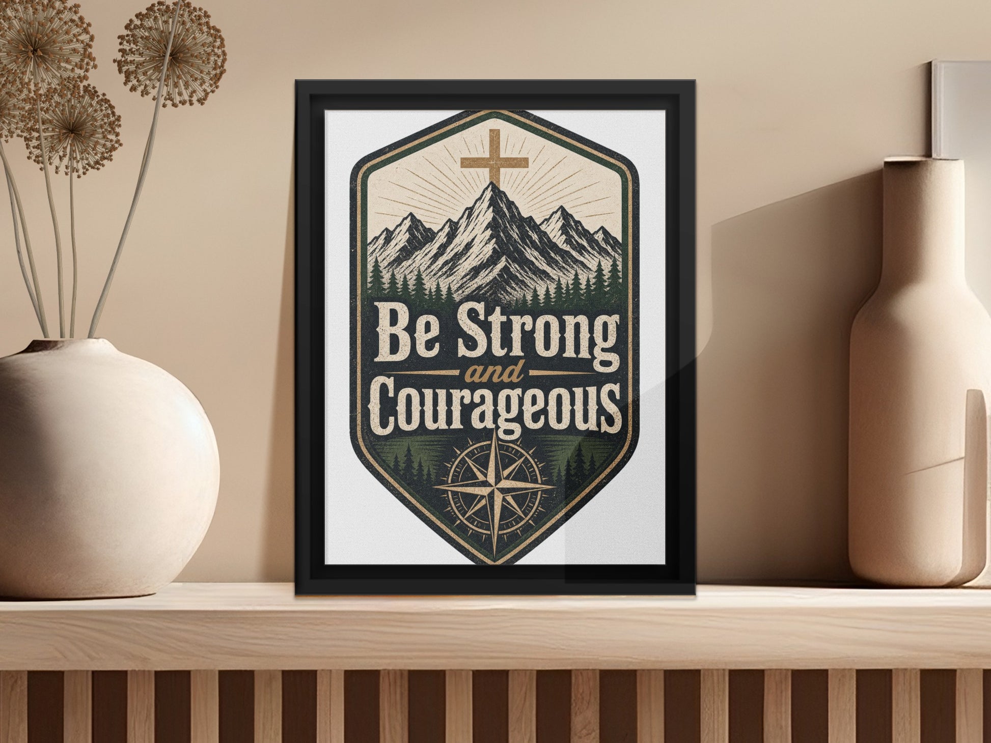 Framed artwork with mountains, trees, compass, and text "Be Strong and Courageous".
