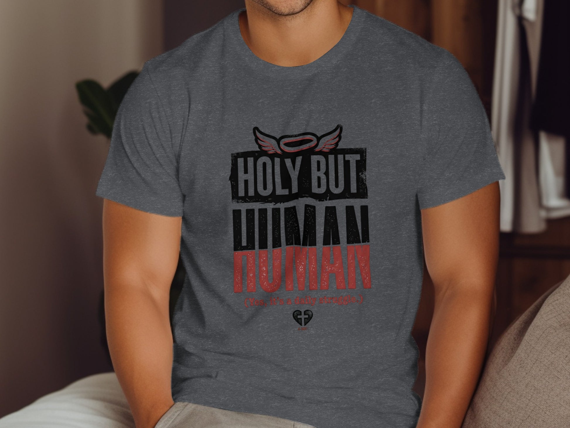 Dark grey t-shirt with text "HOLY BUT HUMAN" and small wings.