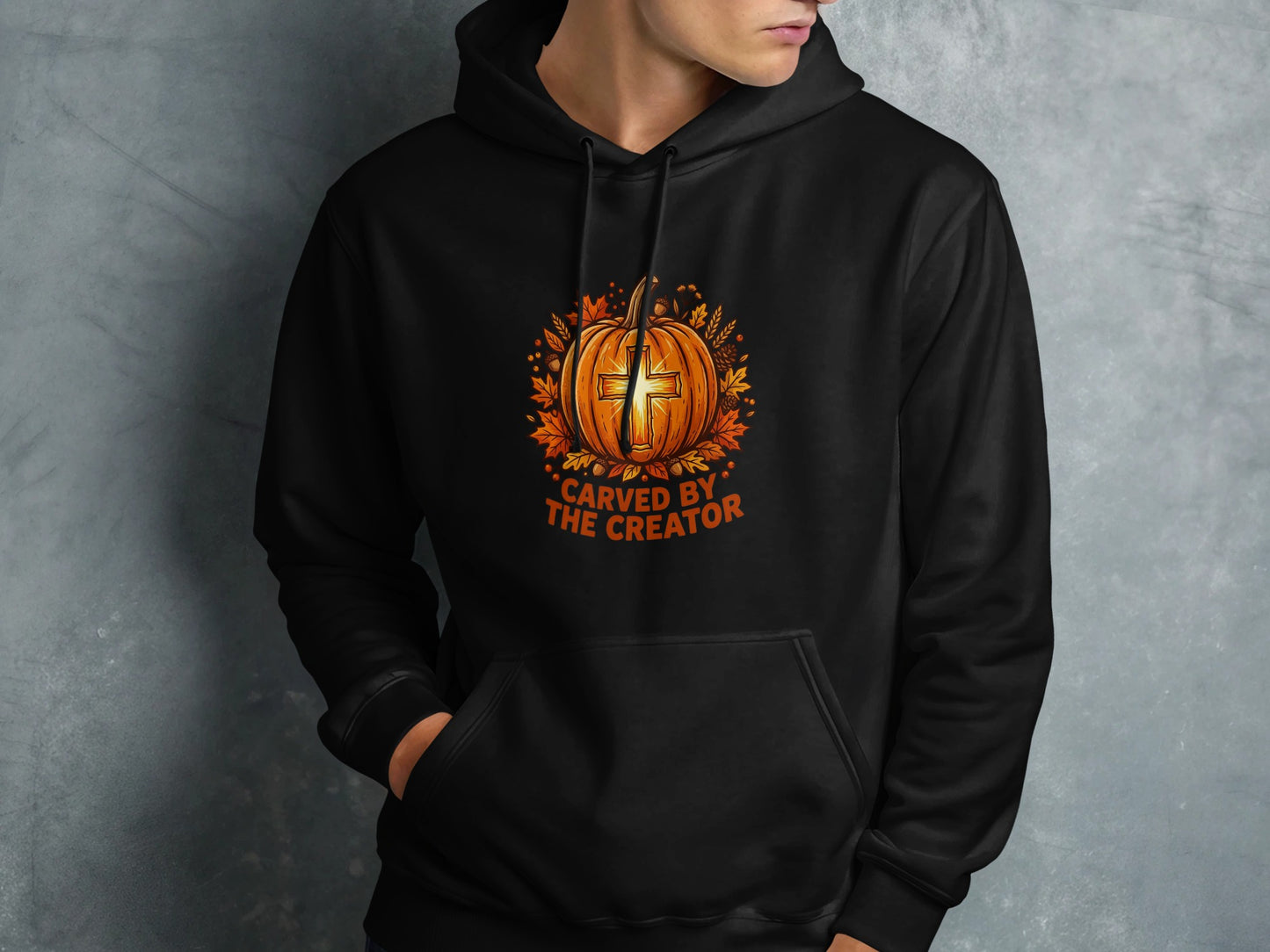 Black hoodie with carved pumpkin and cross design, "CARVED BY THE CREATOR" text.