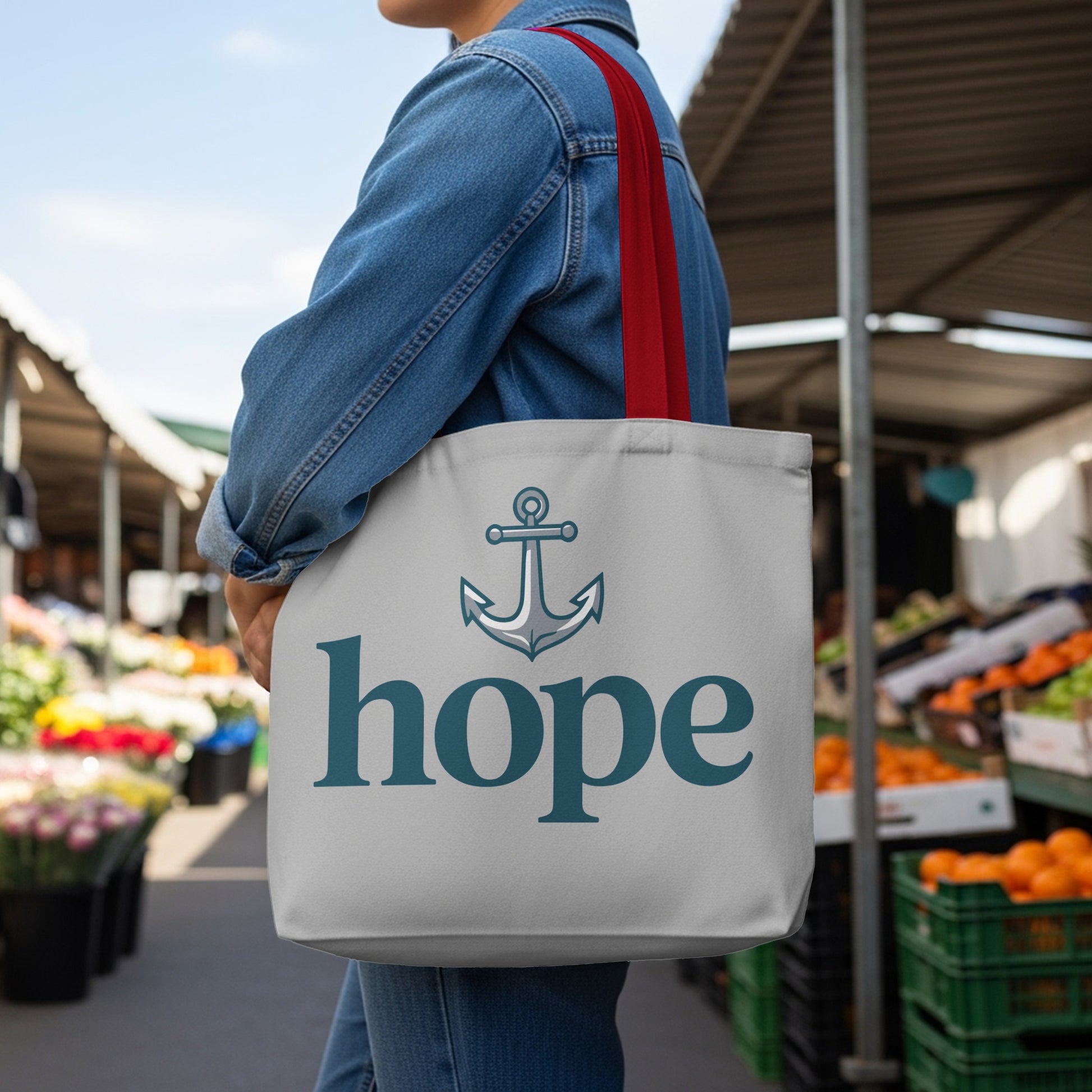 Gray tote bag with anchor and "hope" text, held by a person in denim.