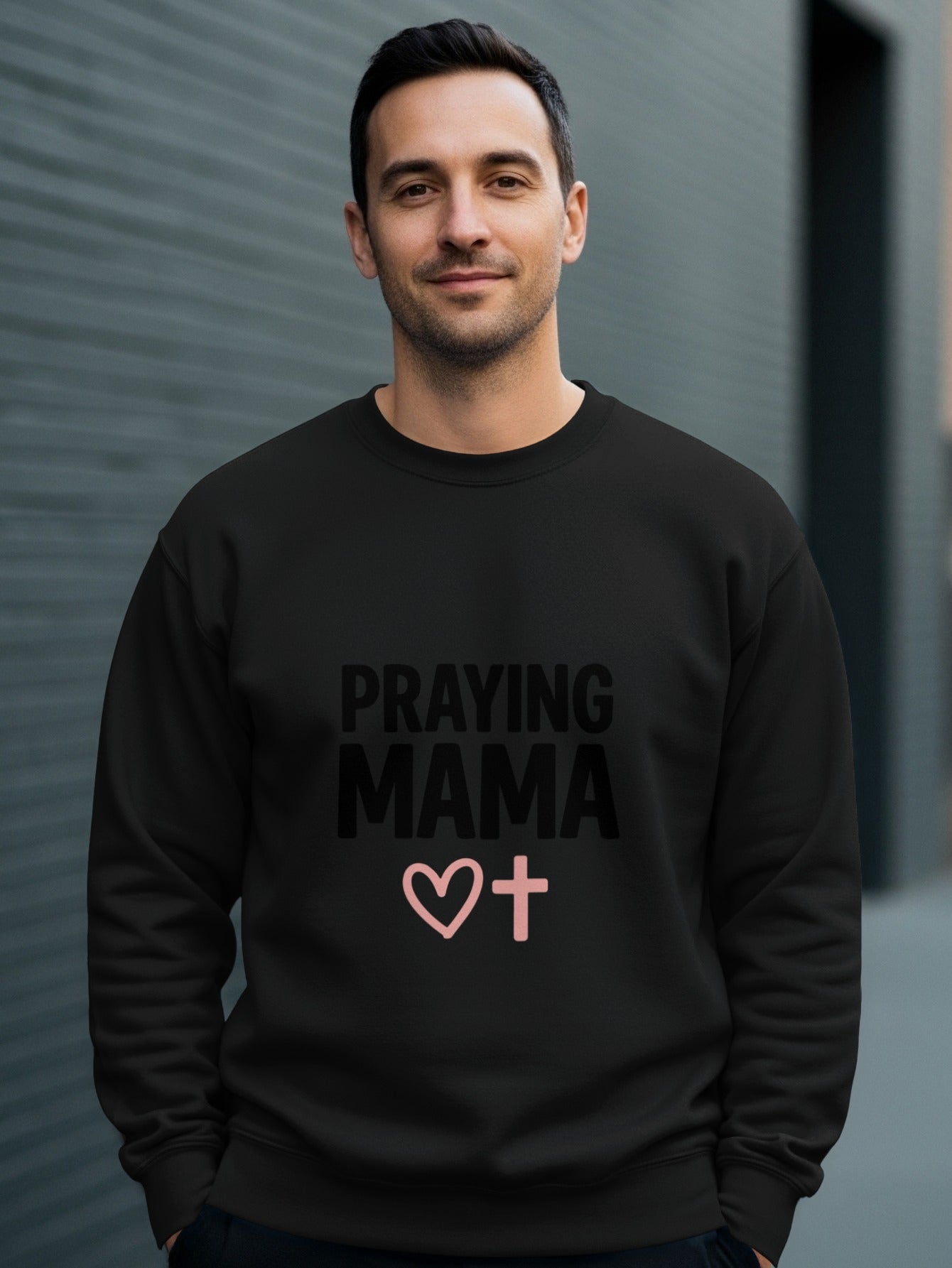 Black sweatshirt with "PRAYING MAMA" text and a pink heart and cross graphic.