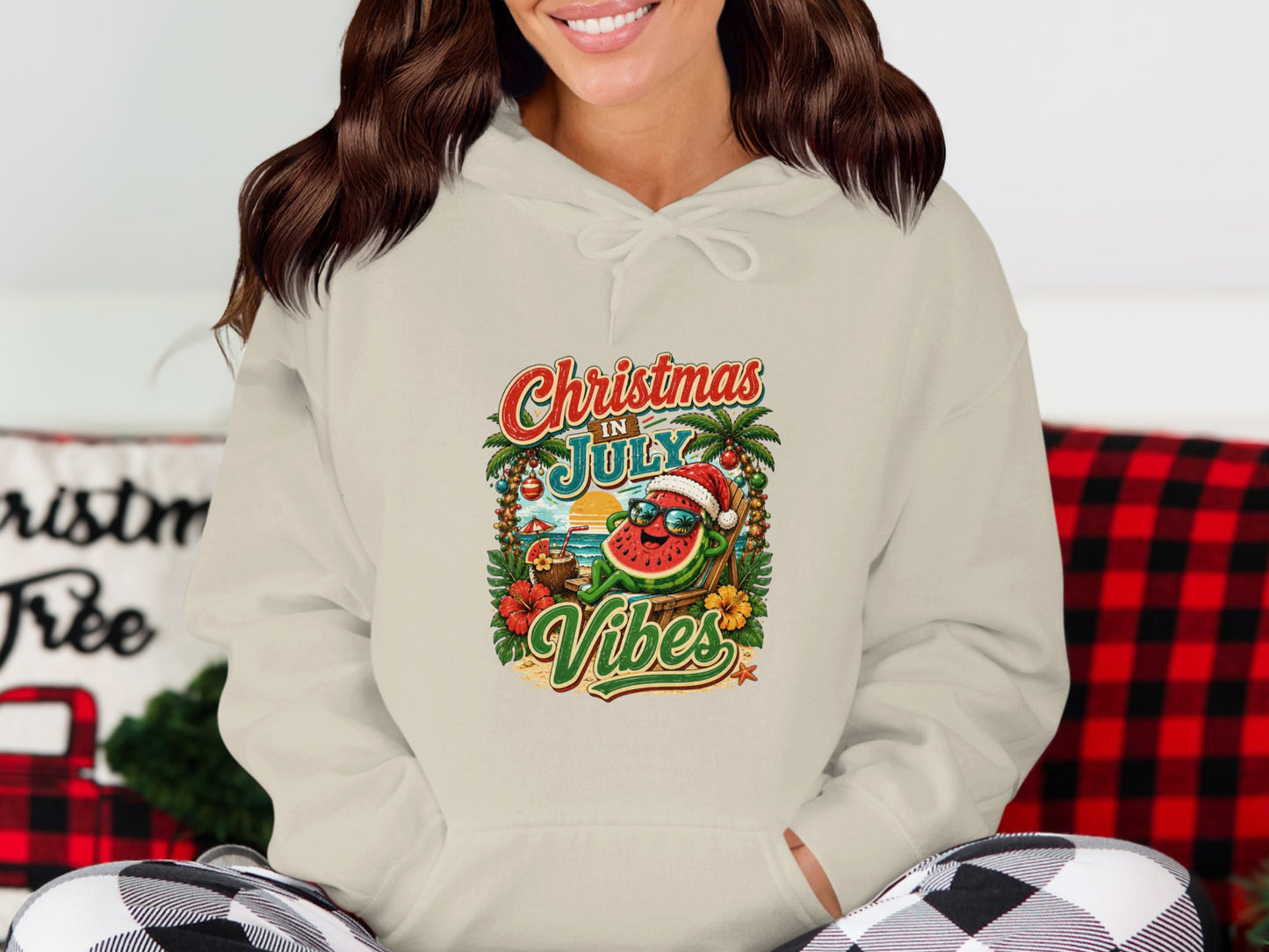 Cream hoodie with a cartoon watermelon wearing sunglasses, on a beach, with "Christmas in July Vibes" text.