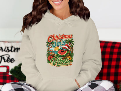 Cream hoodie with a cartoon watermelon wearing sunglasses, on a beach, with "Christmas in July Vibes" text.