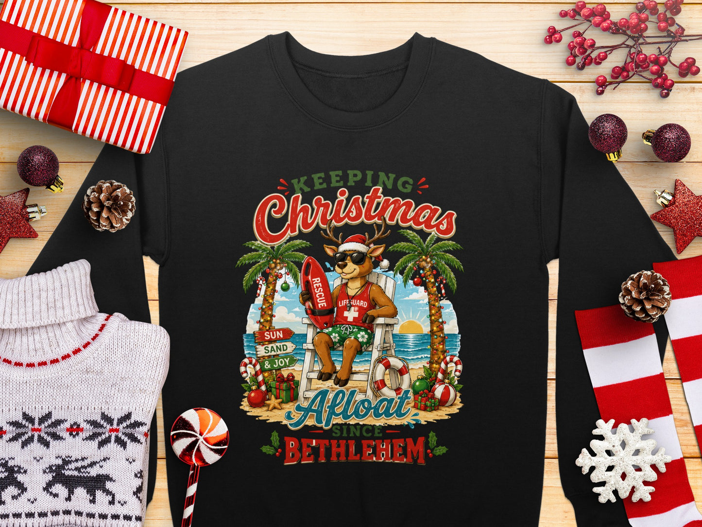 Black sweatshirt with "Keeping Christmas Afloat Since Bethlehem" text and lifeguard reindeer illustration.