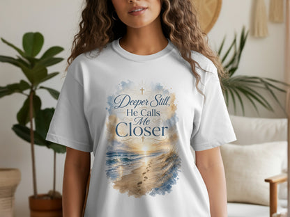 White t-shirt with watercolor beach scene and text "Deeper Still, He Calls Me Closer".
