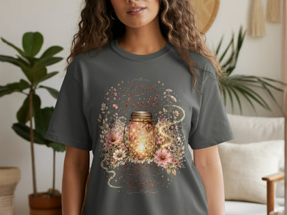 T-shirt with illuminated mason jar, flowers, and text "A Little Faith Lights the Way."