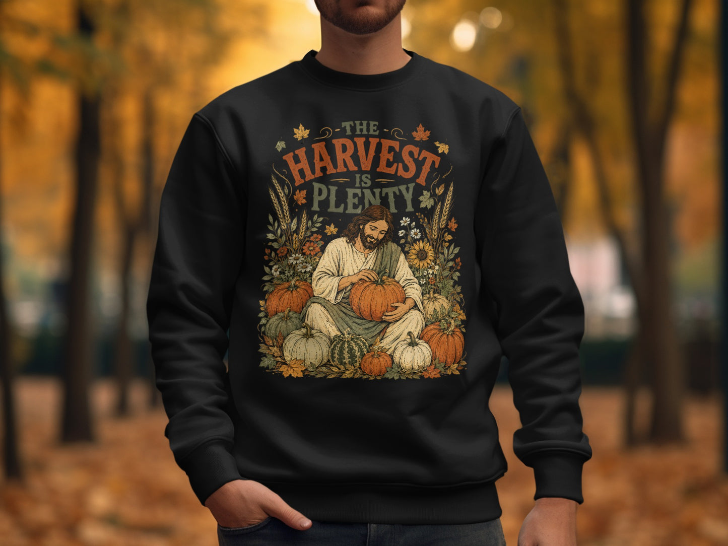 Black sweatshirt with Jesus holding pumpkins, text "The Harvest is Plenty".