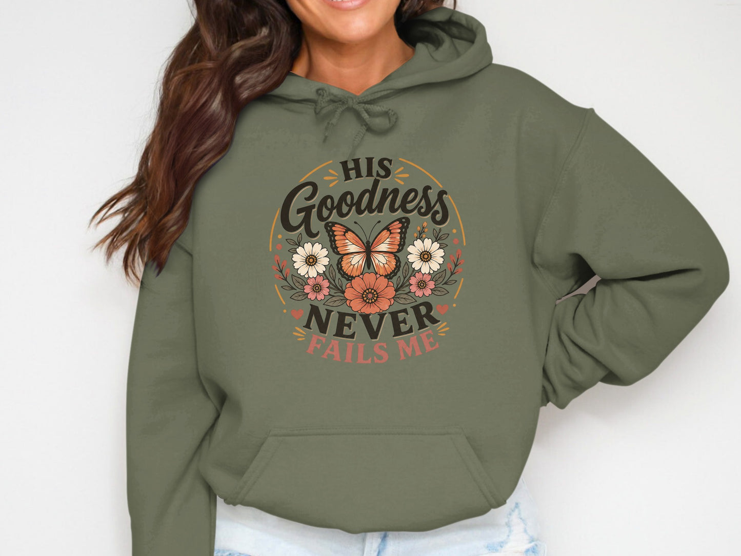 Olive green hoodie with "His Goodness Never Fails Me" text and floral butterfly design.
