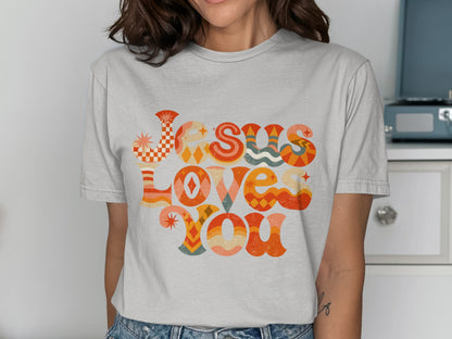 T-shirt with retro-style text "Jesus Loves You" in colorful wavy font.