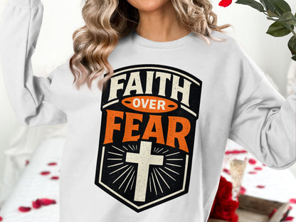 White sweatshirt with "FAITH OVER FEAR" and a cross design.