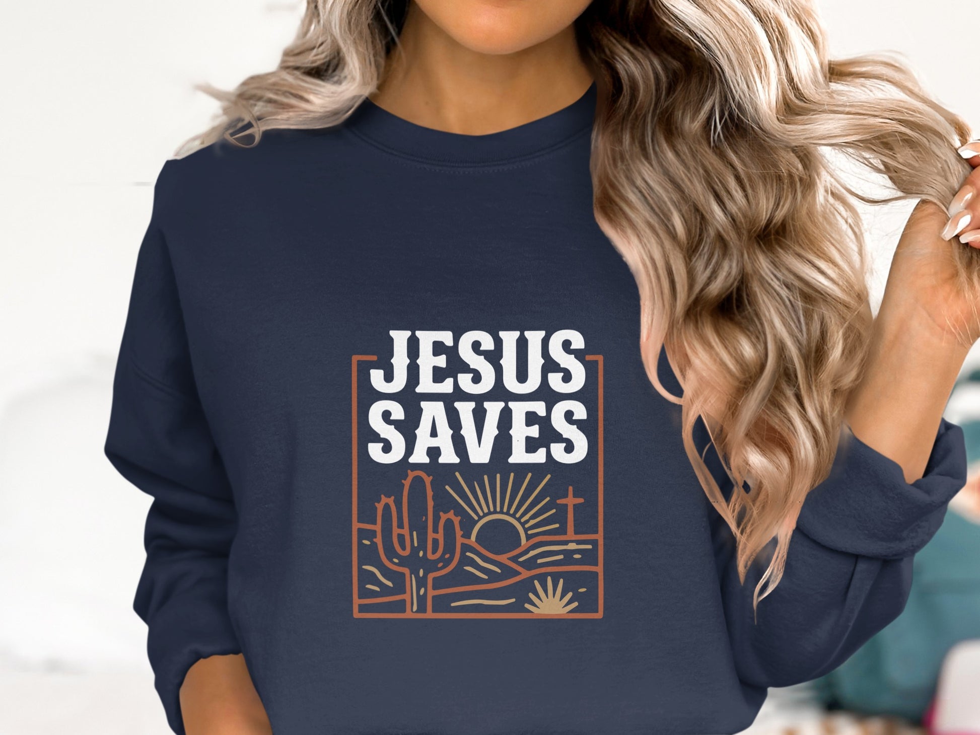 Navy sweatshirt with "Jesus Saves" text, desert landscape, and rising sun graphic.
