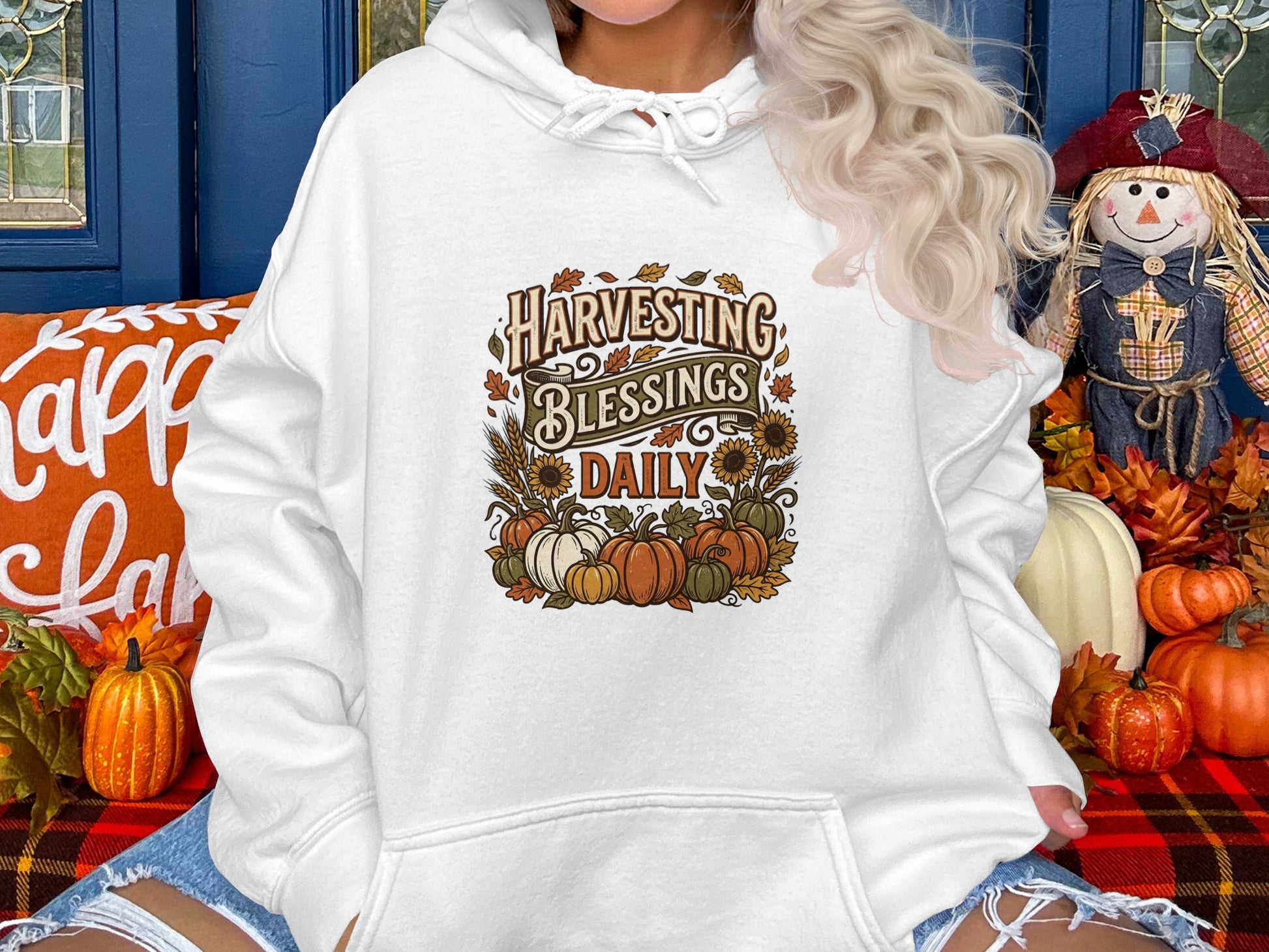 White hoodie with "Harvesting Blessings Daily" text and autumn pumpkin design.