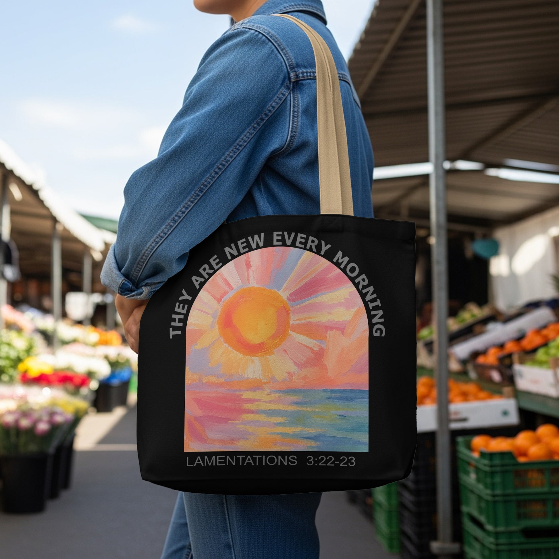 Black tote bag with colorful sunrise over water and text "LAMENTATIONS 3:22-23".