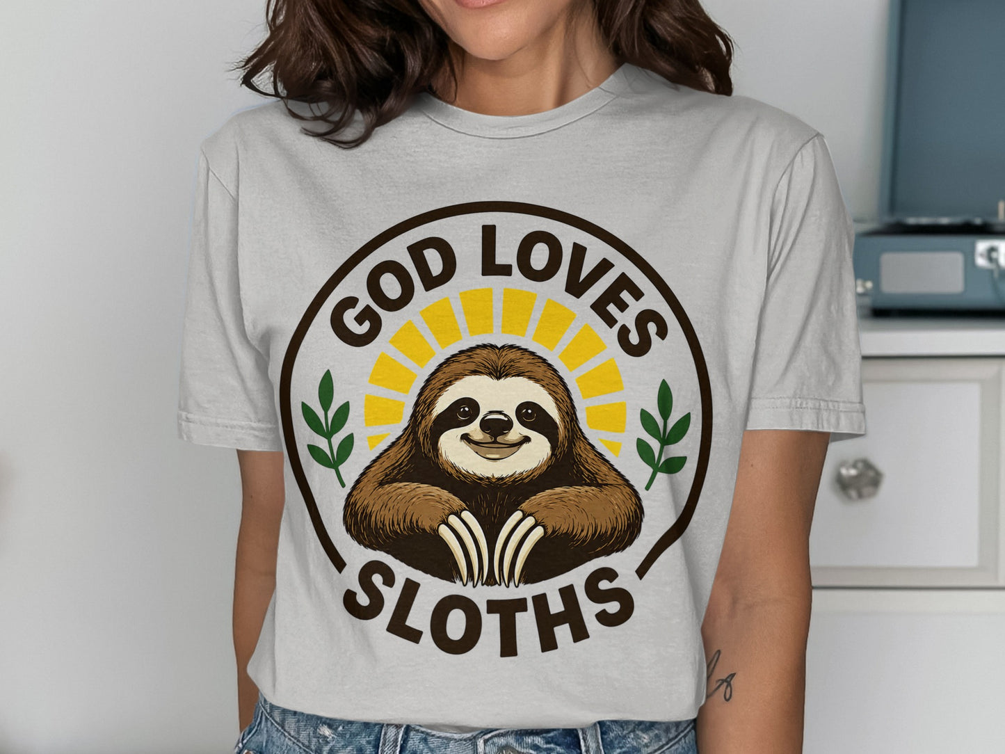 Brown t-shirt with a smiling sloth graphic and "God Loves Sloths" text.